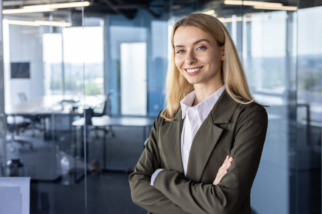 Portrait of a successful and smiling business woman, the founder of the company, the director in a suit standing confidently in the office. crossing his arms on his chest, looking at the camera